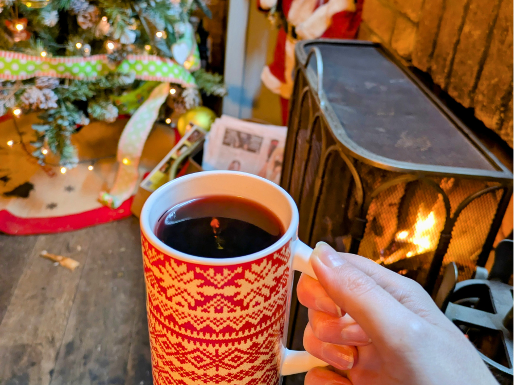 mulled wine by the fireplace next to a christmas tree